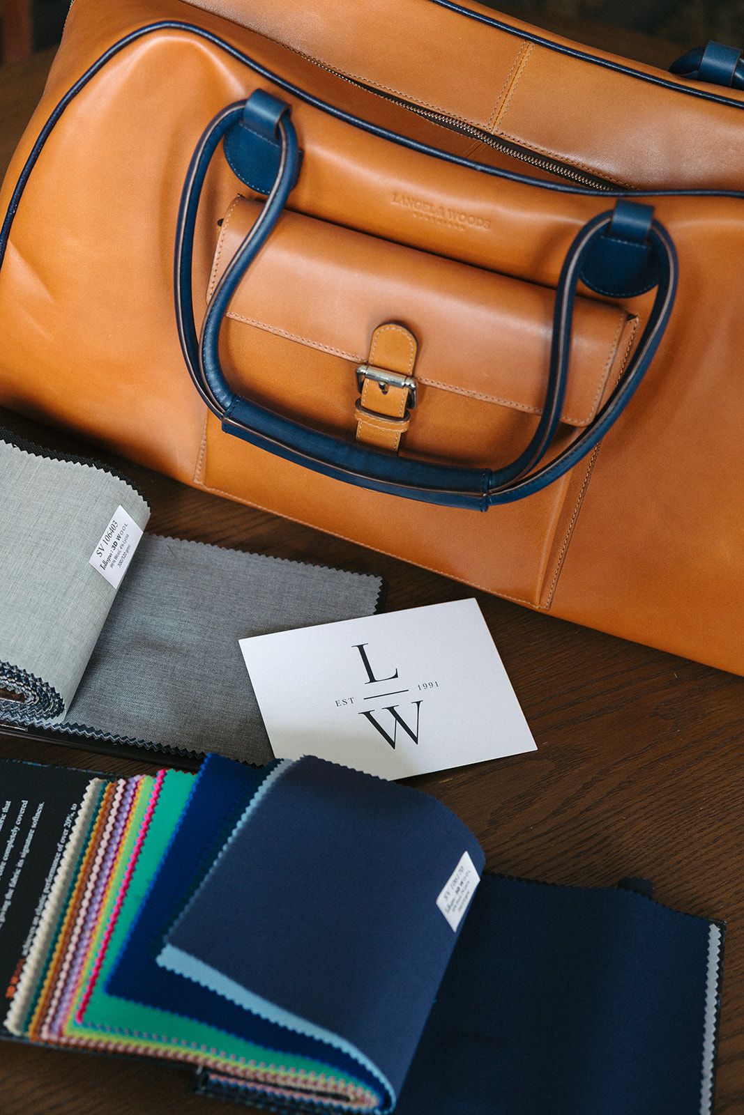 Fabric swatches and a Langel & Woods card beside a leather duffel