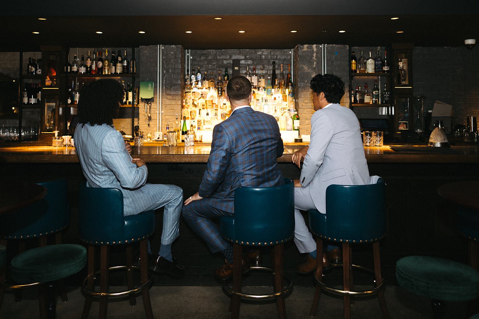 Three clients in custom Langel & Woods suiting seated at a bar