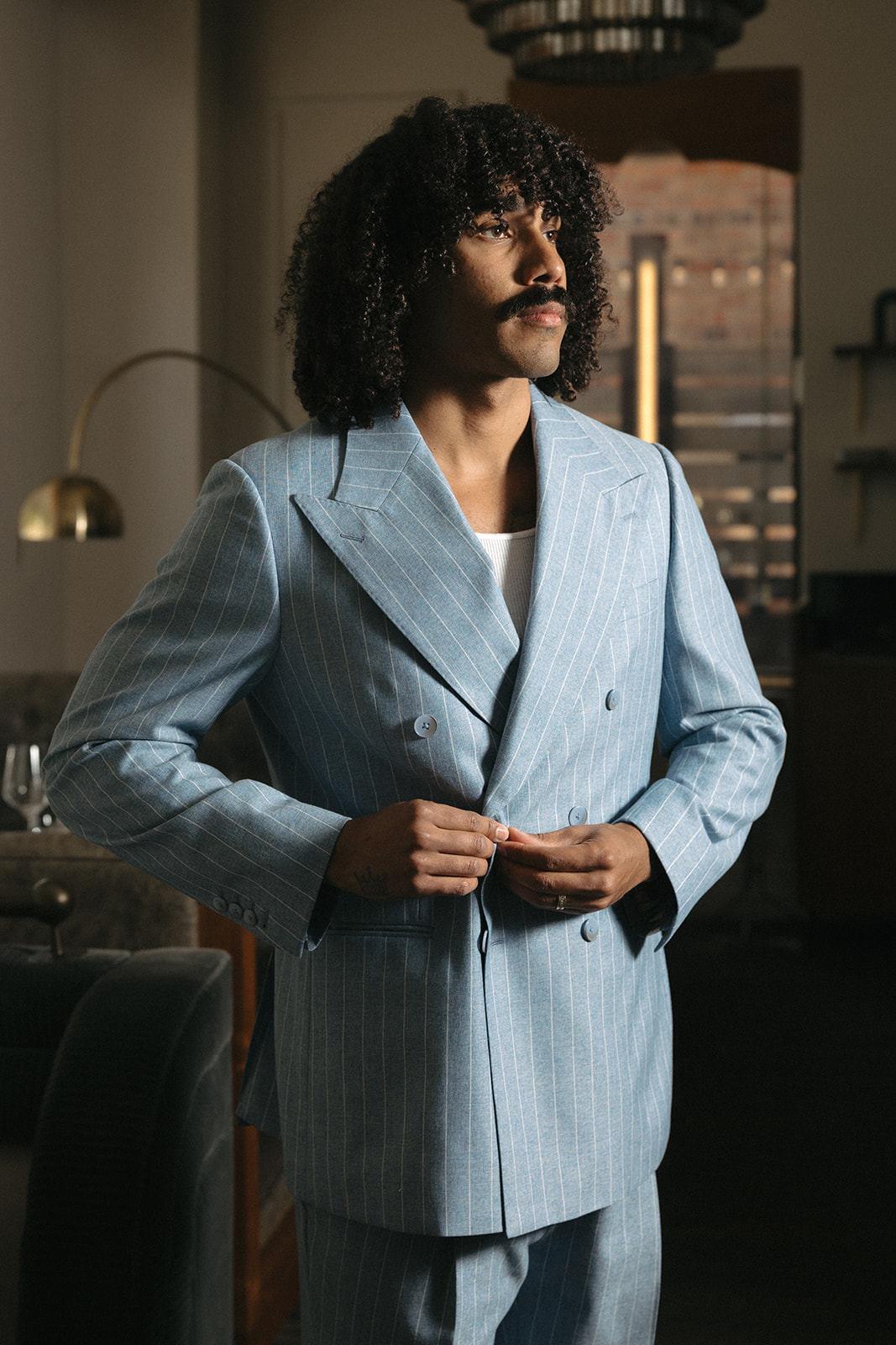 Man buttoning a custom light blue double-breasted suit