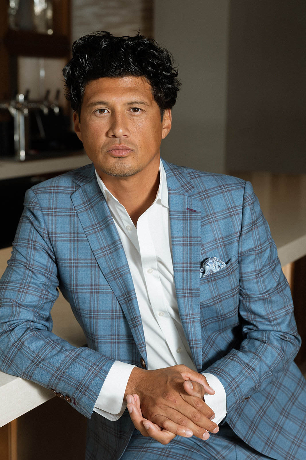 Man seated in a custom blue plaid sport coat