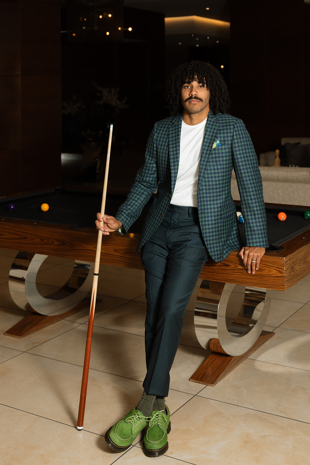 Man in a custom green check jacket at a pool table