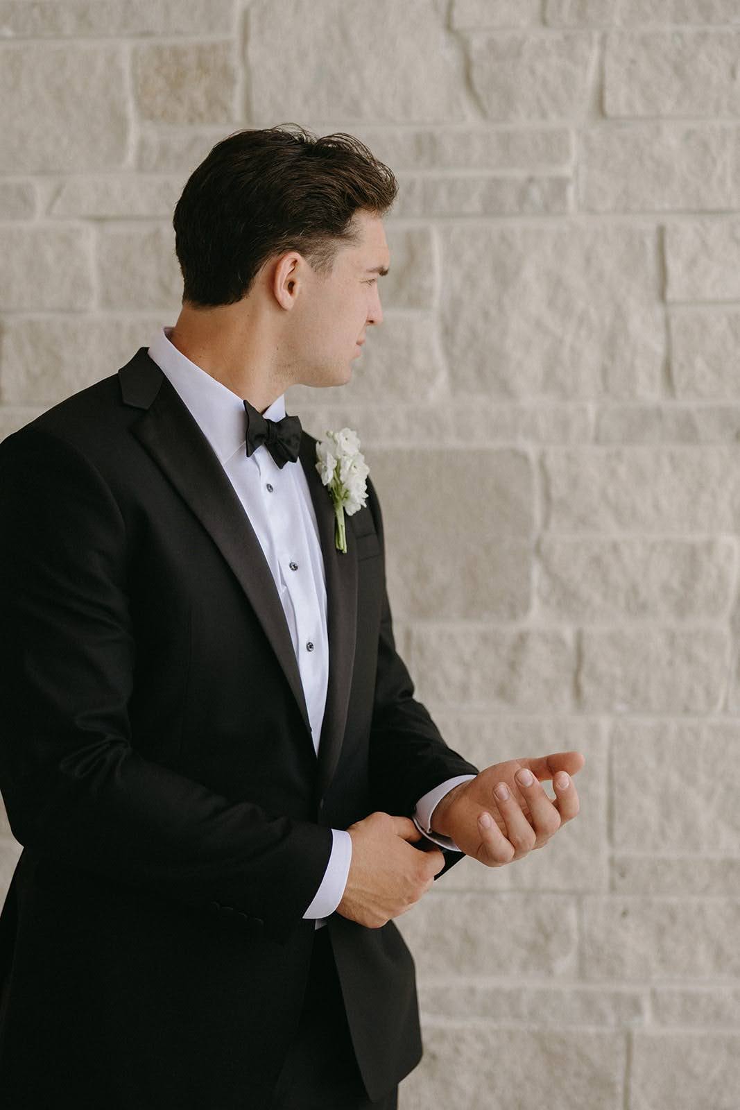Groom in a custom black tuxedo with a boutonniere