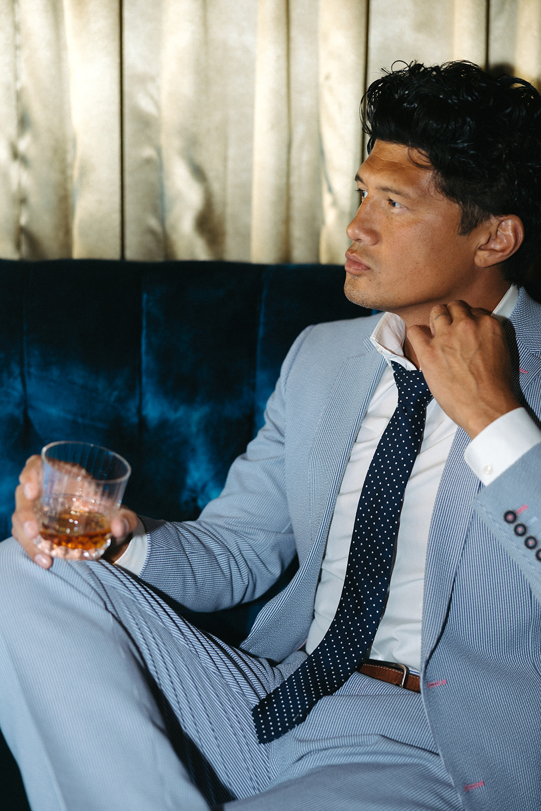 Man in a custom light blue suit holding a drink