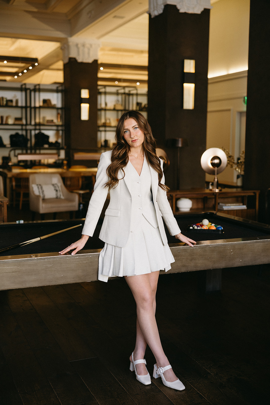 Woman in a custom cream blazer and pleated skirt