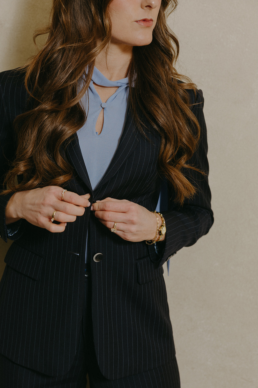 Woman buttoning a custom navy pinstripe blazer